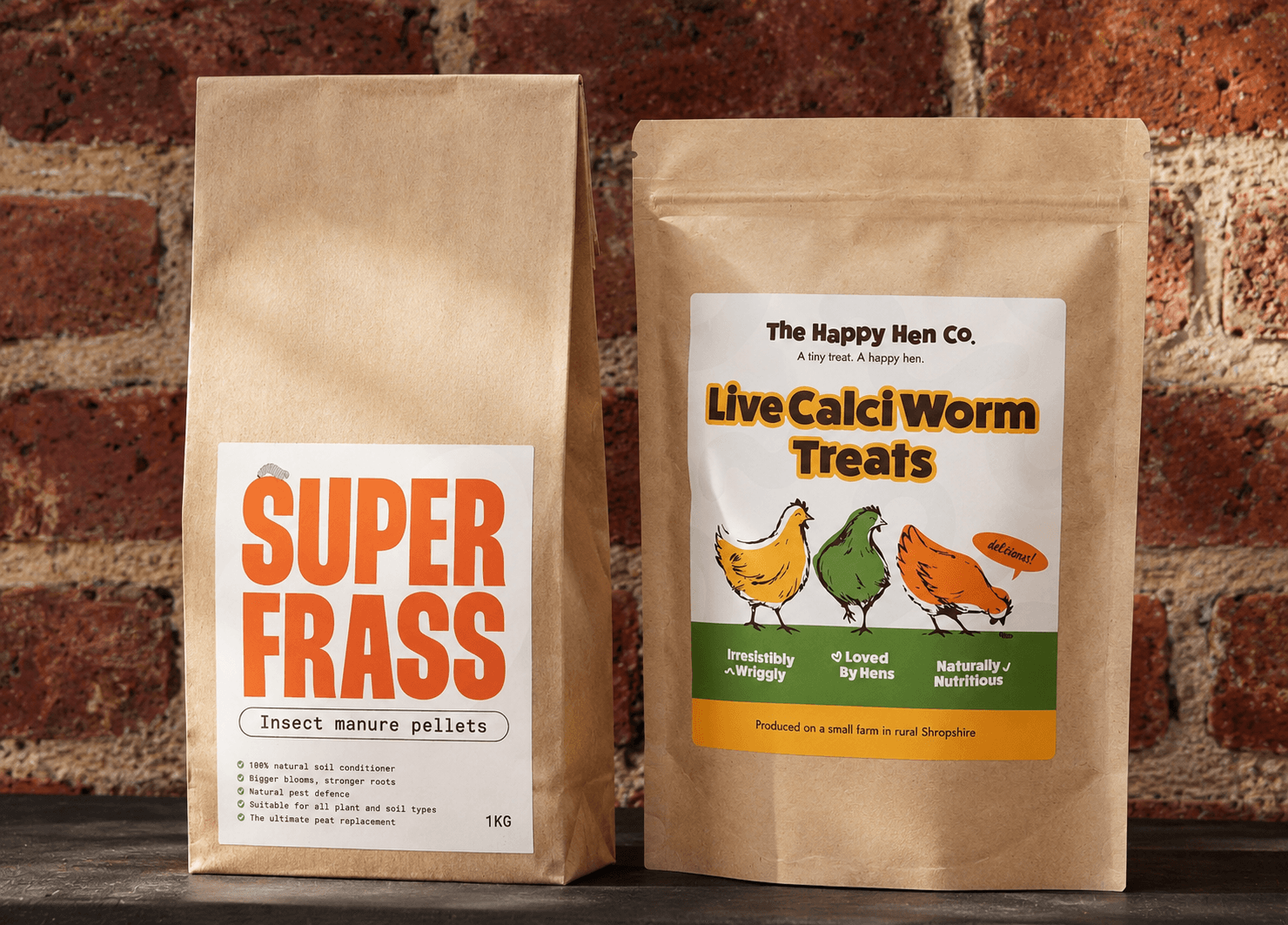 The Happy Hen Co. Live Calci Worm Treats and Superfrass packs on a brick background