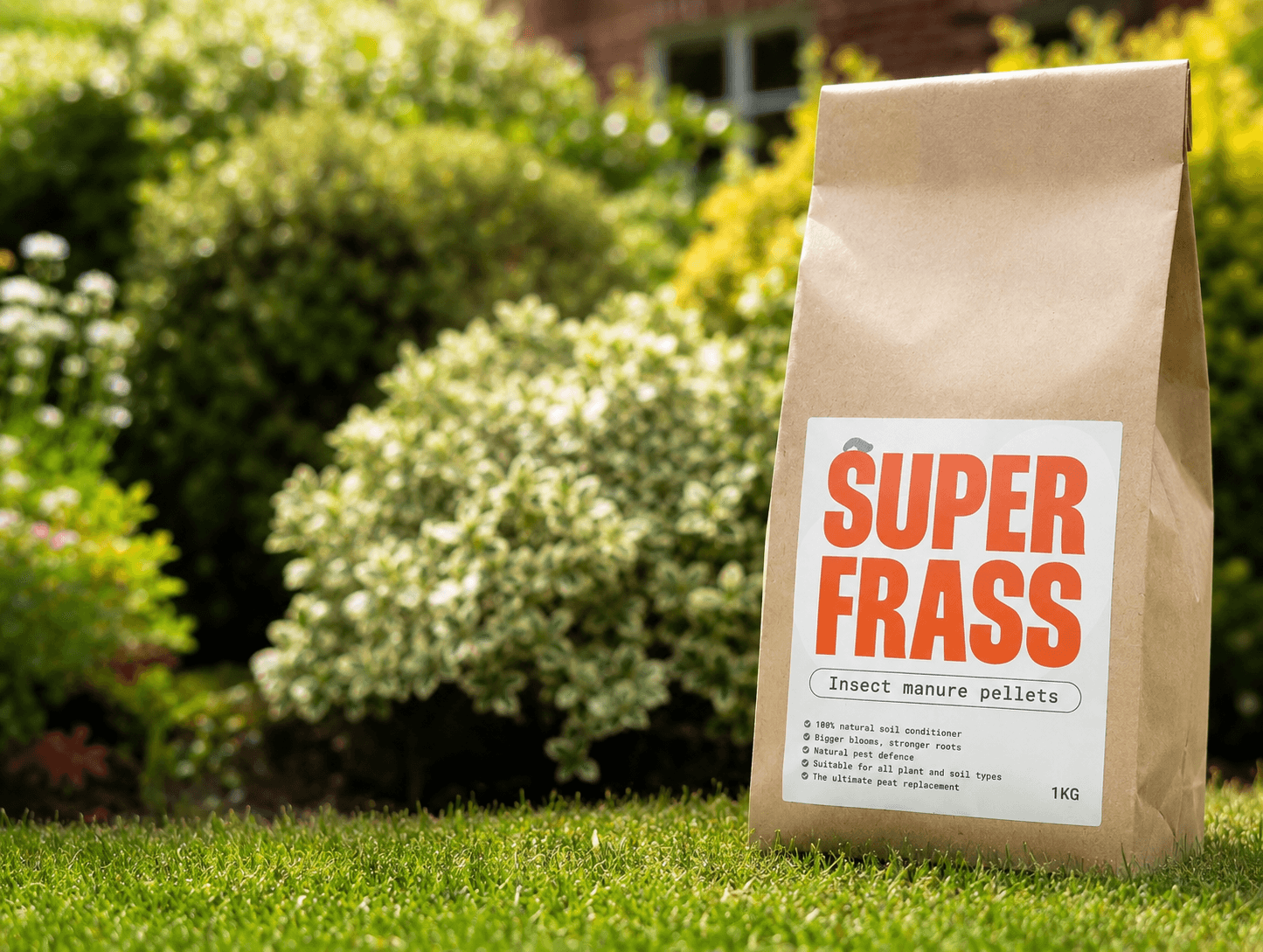 Superfrass insect manure pellets pack standing on a lawn with garden bushes in the background